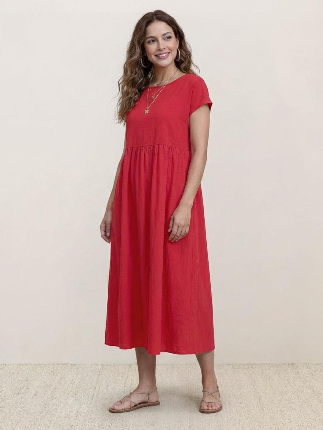 Woman wearing capped-sleeve voluminous pleated midi dress with flowing silhouette and flat stomach drape