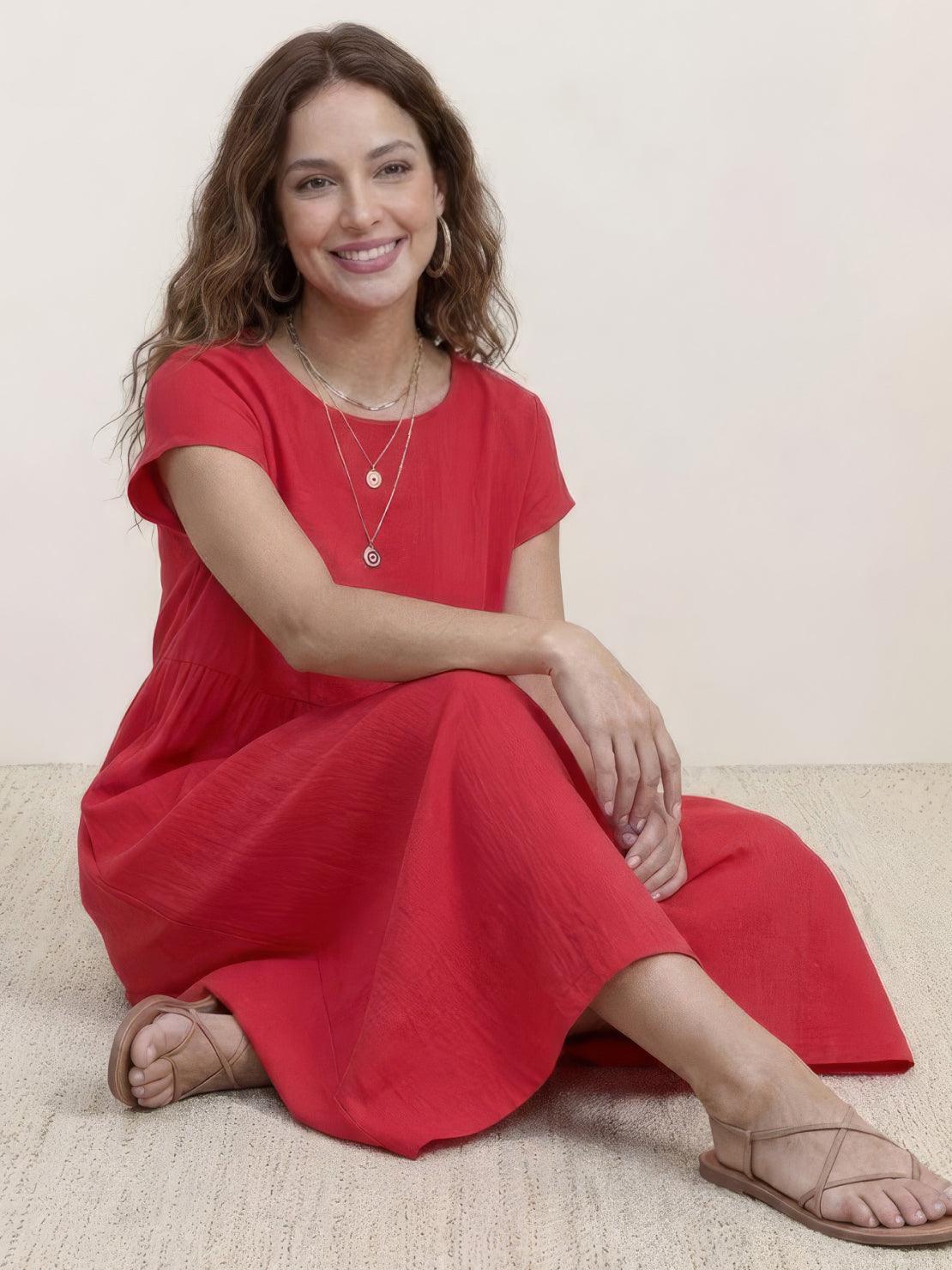 Woman wearing a capped-sleeve voluminous pleated midi dress with a flowing skirt and gathered waist