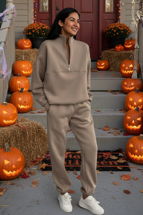 woman wearing beige cotton-blended two-piece tracksuit standing on Halloween decorated porch with pumpkins and skeletons