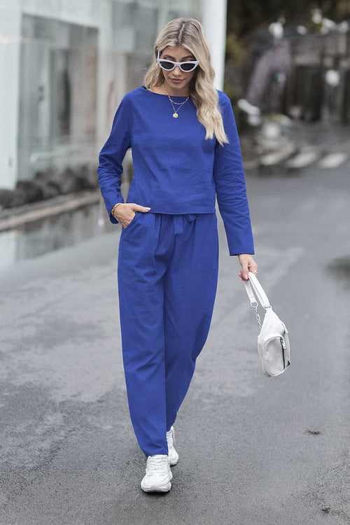 Woman wearing blue cotton-linen monochrome capsule set with longline top and wide-leg pants walking outdoors with white sneakers and handbag