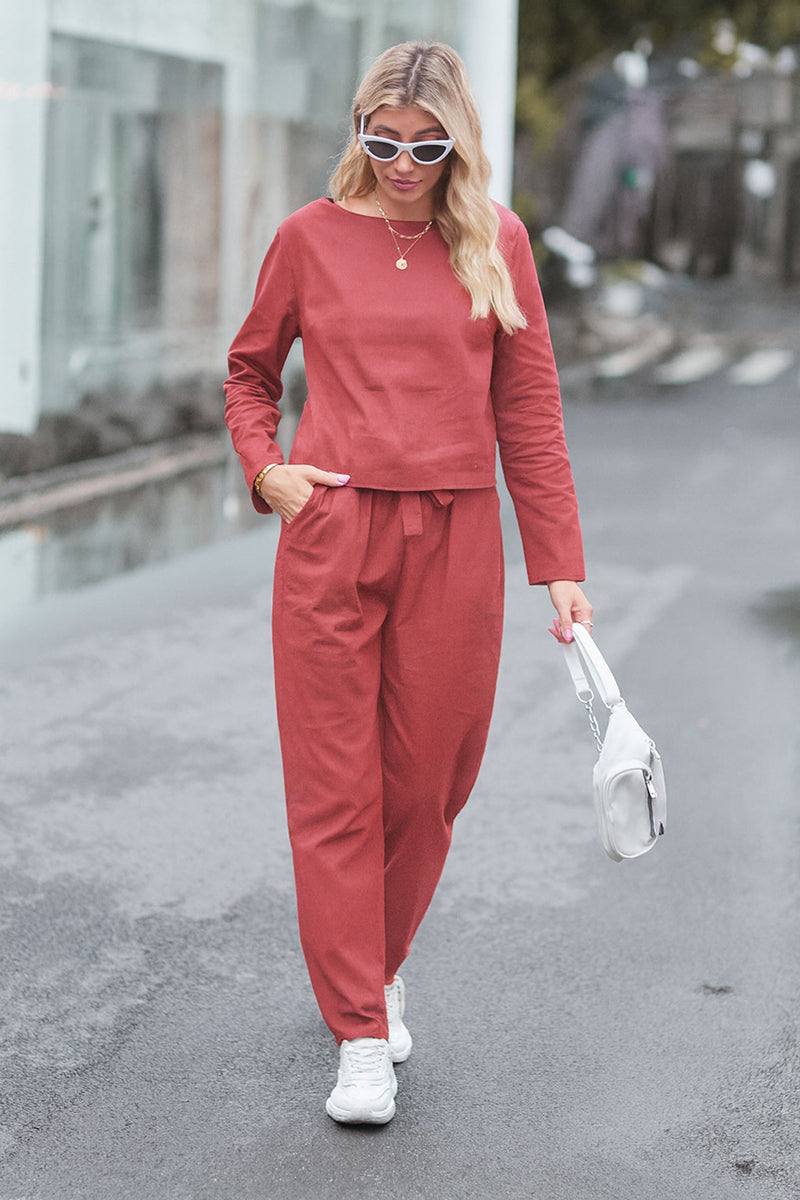 Woman wearing a relaxed cotton-linen monochrome capsule set with longline top and wide-leg pants in rust color walking outdoors