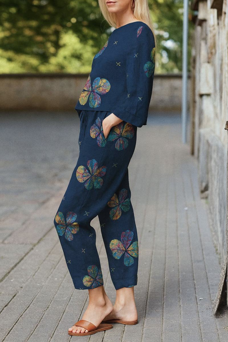 Woman wearing navy blue cotton-linen monochrome set with colorful floral prints, relaxed longline top and wide-leg pants, casual outdoor setting