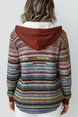 Back view of a woman wearing a striped multicolored Highland Plaid Shacket with a rust-colored hood and fleece lining.
