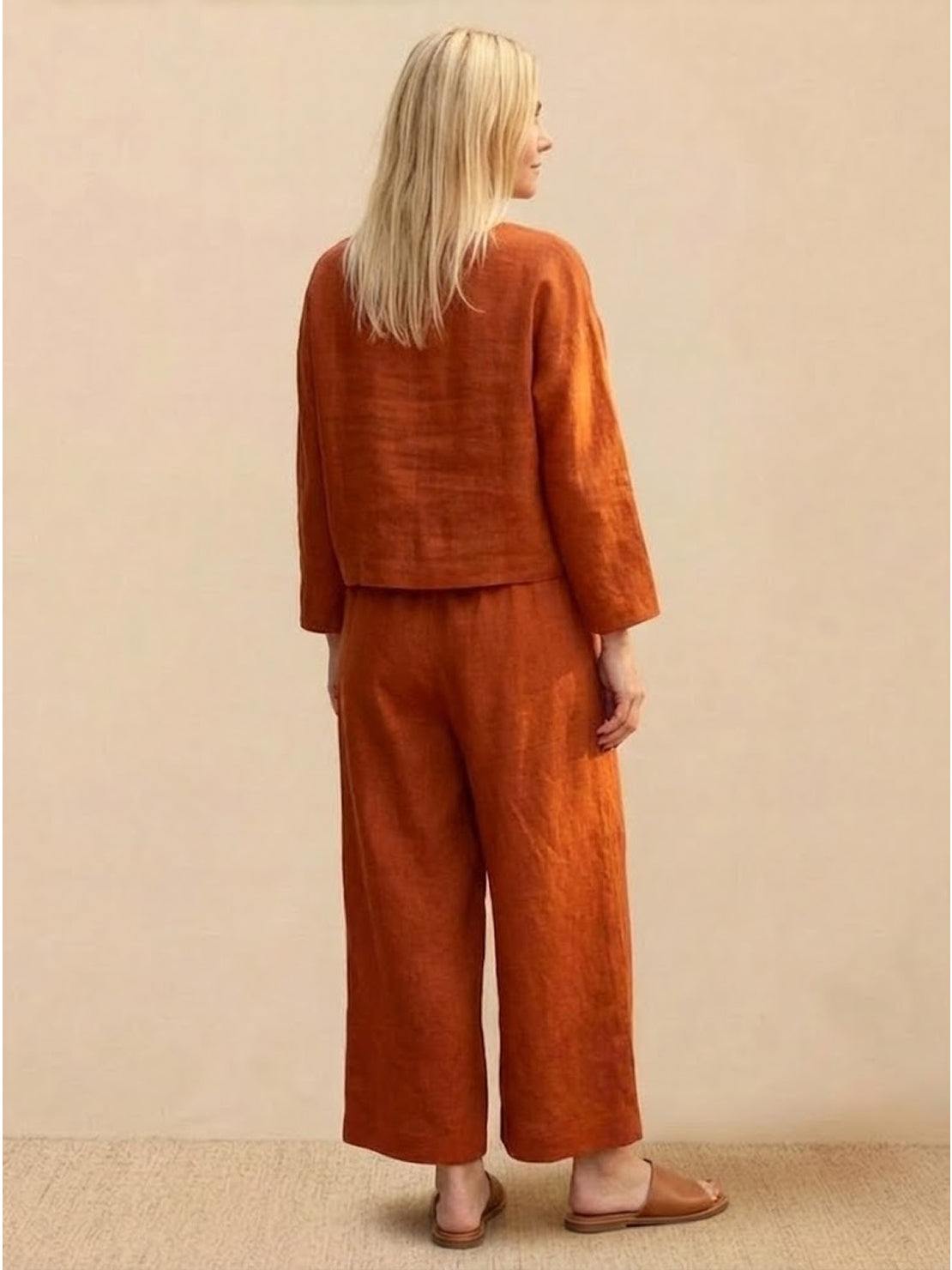 Woman wearing loose solid color burnt orange two-piece set with long sleeves and wide-leg pants, back view