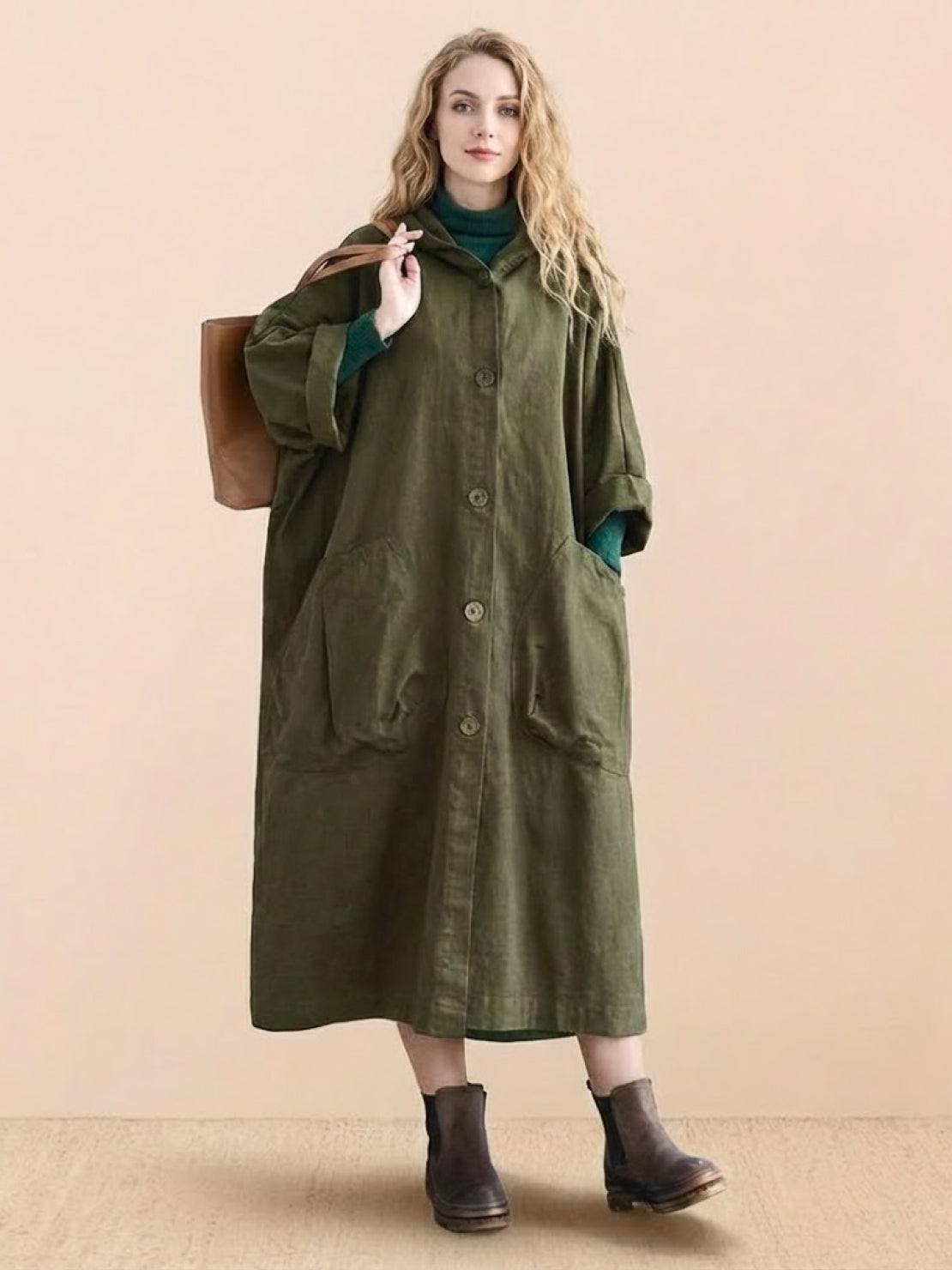 Woman wearing oversized olive green waterproof design windbreaker jacket with large pockets and attached hood