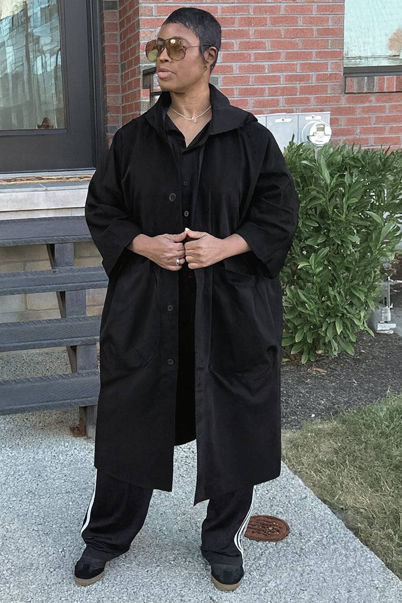 Oversized black water-resistant windbreaker jacket with snap-button closure and large pockets