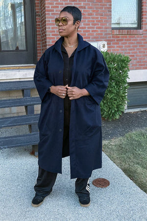 One size navy oversized water resistant windbreaker jacket with large pockets and snap-button closure worn outdoors
