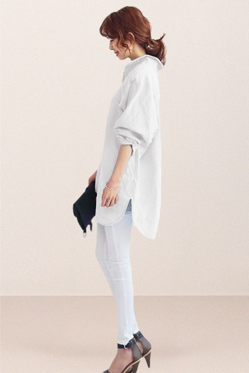 Woman wearing white oversized linen shirt with loose sleeves and flowing hemline, styled with white pants and heels.
