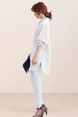 Woman wearing oversized white linen shirt with rolled sleeves and high-low hem