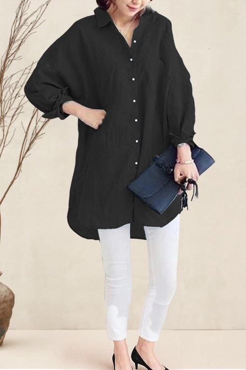 Black oversized linen shirt with relaxed fit, long sleeves, button front, and flowing hemline styled with white pants and clutch.