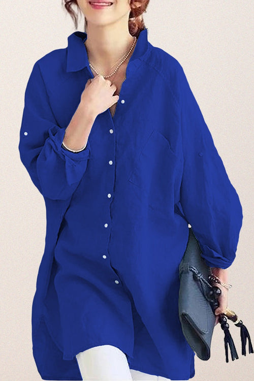 Woman wearing oversized blue linen shirt holding gray bag with tassels