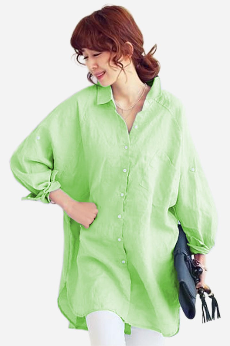 Woman wearing oversized lime green linen shirt with loose sleeves and button front, holding a black clutch bag.