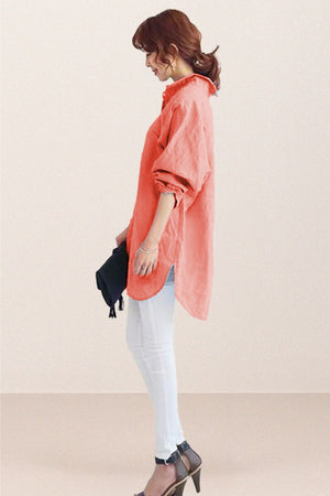 Woman wearing oversized linen shirt in sun-washed pink with rolled sleeves and white pants