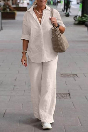 Woman wearing oversized 100% cotton shirt and wide-leg pants co-ord set walking outdoors with a tote bag and white sneakers