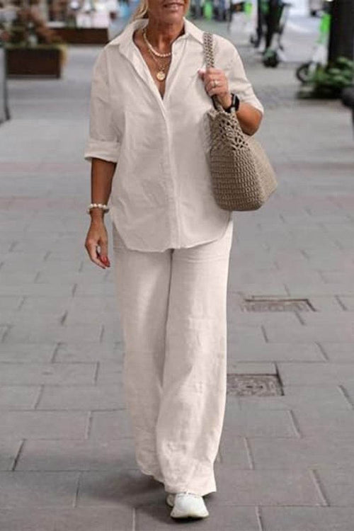 Woman wearing oversized 100% cotton shirt and wide-leg pants co-ord set walking outdoors with a tote bag and white sneakers