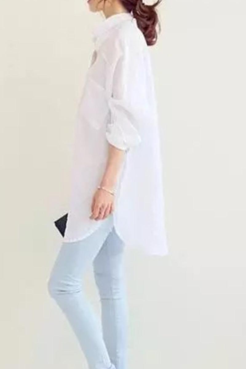 Woman wearing a white oversized linen shirt with rolled sleeves and light blue jeans, side view