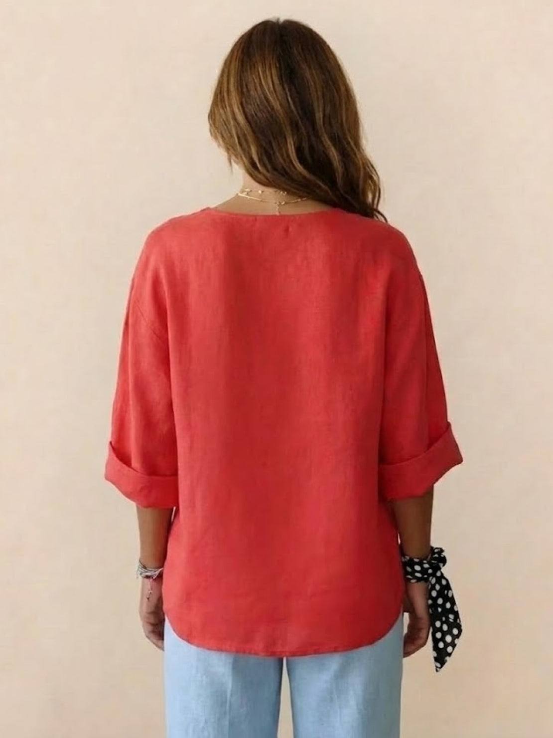 Back view of woman wearing coral Pure Linen Age-Defying Shirt with rolled sleeves and light blue pants