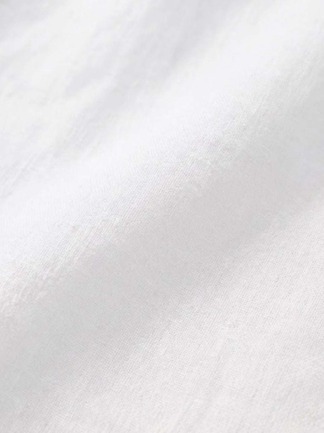 Close-up of soft white relaxed loose breathable linen fabric texture