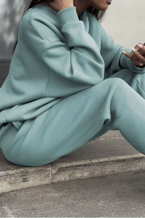 Woman wearing mint green cotton blend tracksuit sitting outdoors with phone in hand