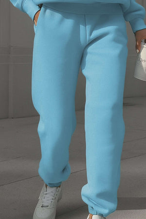 Light blue cotton blend tracksuit pants with stretch waistband and cuffs, styled with white sneakers.