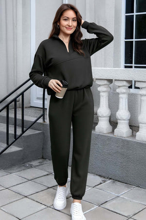woman wearing dark green cotton blend tracksuit with half zipper and elastic cuffs holding a coffee cup outdoors