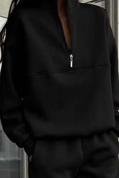 Woman wearing a black cotton blend tracksuit with a half-zip high collar and relaxed fit