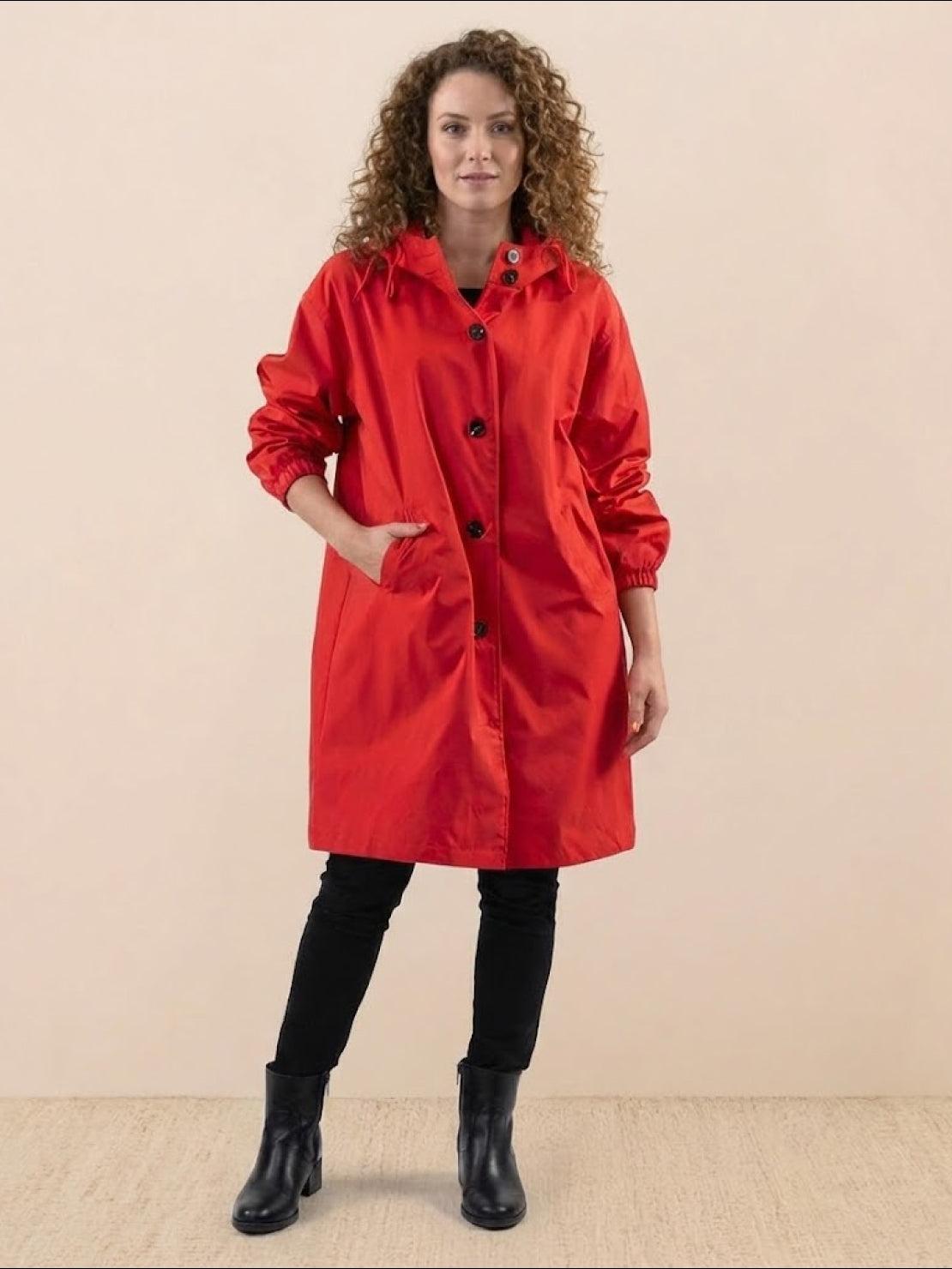 Woman wearing trendy oversized red Rain Couture Windbreaker windproof water-resistant jacket with hood and pockets
