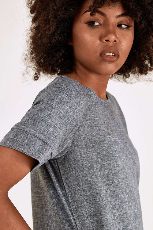 Woman wearing grey short sleeve shift dress with round neck and side pockets