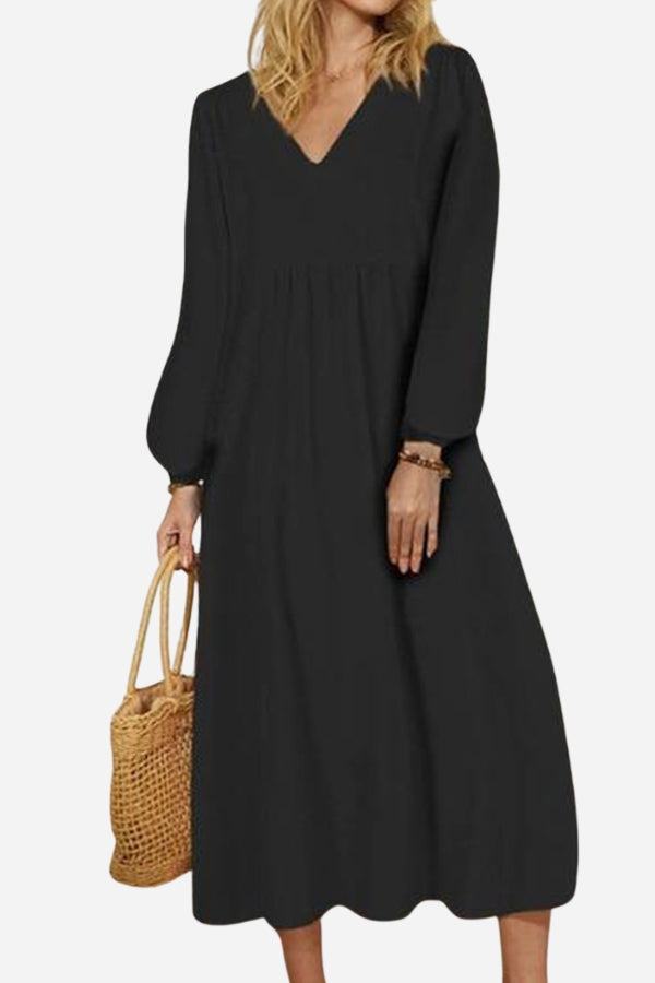 Woman wearing black midi long sleeve spring dress with V-neck and loose fit, holding woven handbag