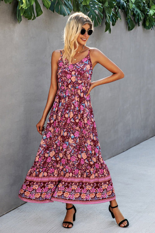 Woman wearing a vintage flower prints maxi dress with spaghetti straps and open back standing outdoors