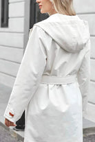White water-resistant windbreaker trench jacket with hood and adjustable belt on woman outdoors