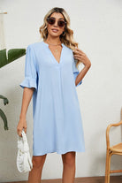Woman wearing light blue Dainty Charm Casual Ruffle Dress with ruffled V-neck and short sleeves holding white bag