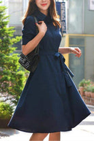 Woman wearing navy radiance belted shirt dress with a classic collar and detachable belt, styled for a casual outdoor setting.