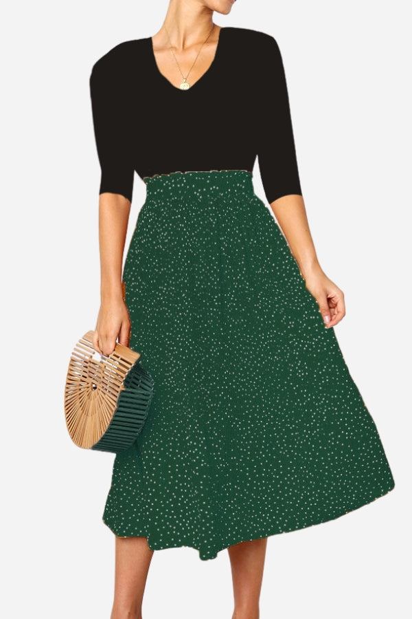 Woman wearing effortlessly chic polka dot pleated midi skirt with high waist and black top holding bamboo handbag