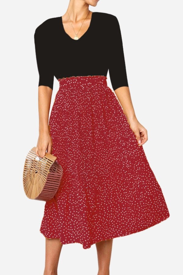 Woman wearing an effortlessly chic polka dot pleated midi skirt with a black top and wooden handbag