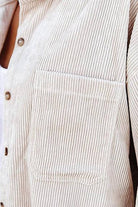 Close-up of beige sleek suede oversized button-down shirt with textured fabric and front pocket detail