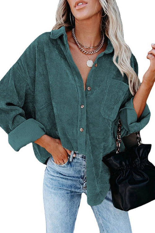 woman wearing teal sleek suede oversized button-down shirt with rolled sleeves and light blue jeans carrying black handbag