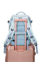 Chic Wanderlust Waterproof Backpack in light blue attached to rose gold suitcase handle showing padded ergonomic straps