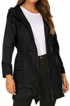 Woman wearing black outdoor and travel hooded raincoat windbreaker jacket with front pockets and zipper closure