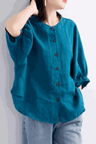 Relaxed loose breathable linen blouse in teal with button-down front and three-quarter sleeves.