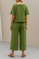 Back view of a woman wearing a green loose fit co-ord set with relaxed short sleeve top and wide-leg cropped pants paired with sandals.