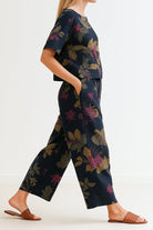 Woman wearing a floral loose fit co-ord set with wide-leg trousers and a relaxed short-sleeve top, styled casually with sandals