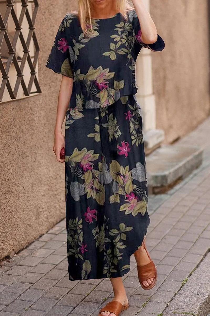 Woman wearing a loose fit co-ord set with a dark floral print, featuring a relaxed short-sleeve top and wide-leg bottoms, styled with brown sandals on a city sidewalk.
