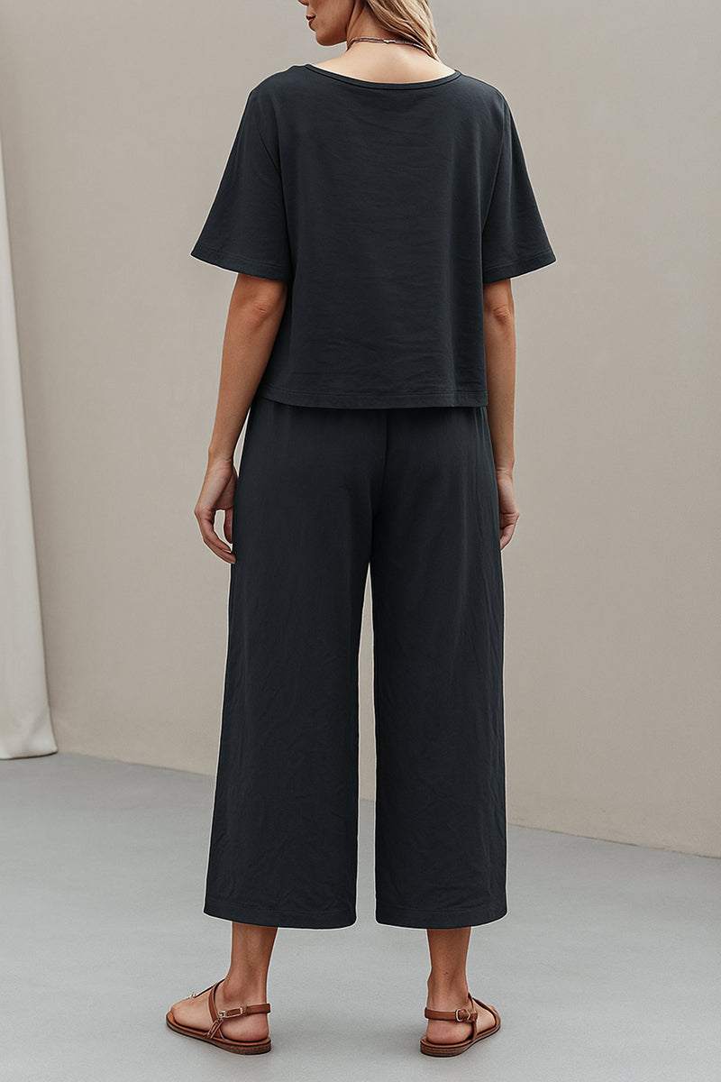 Back view of a woman wearing a black loose fit co-ord set with wide-leg pants and short-sleeve top.