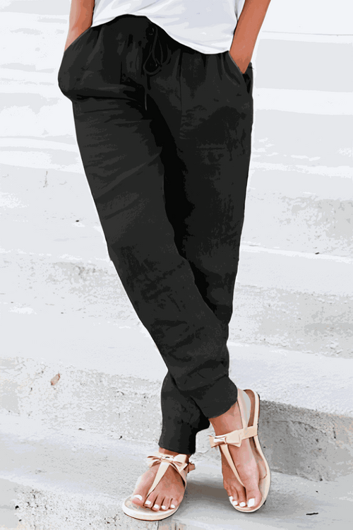Woman wearing black relaxed chic elastic ankles pants with pockets and white top, standing on concrete steps