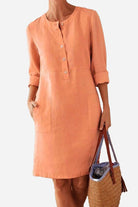 Women’s peach cotton dress with 3/4 rolled sleeves, button front, and pockets in casual summer style