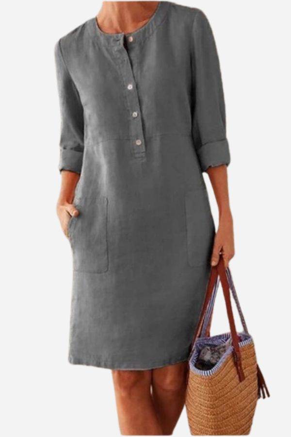 Gray casual cotton dress with ¾ rolled sleeves and front buttons, featuring pockets and a simple waist seam, styled with a wicker handbag.