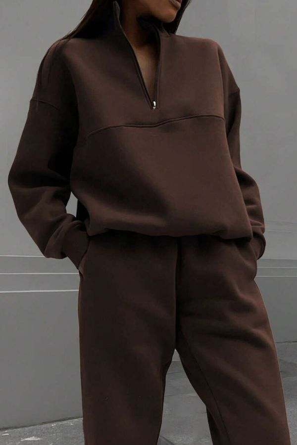 Woman wearing a brown cotton-blended two-piece tracksuit with high collar and deep zipper.