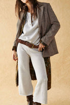 Woman wearing multi-weather comfort two-piece oversized set with cropped wide pants and relaxed top layered with checkered blazer and brown belt