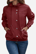 Women's outdoor hooded raincoat and windbreaker in red with button closure and elastic cuffs.